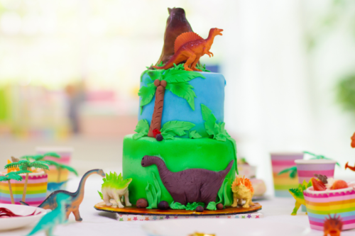 Dinosaur party table setting with dinosaur and volcano birthday cake.