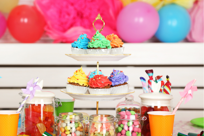 Rainbow birthday party ideas with colorful balloons, rainbow cupcake icing and colorful candy and lollies,